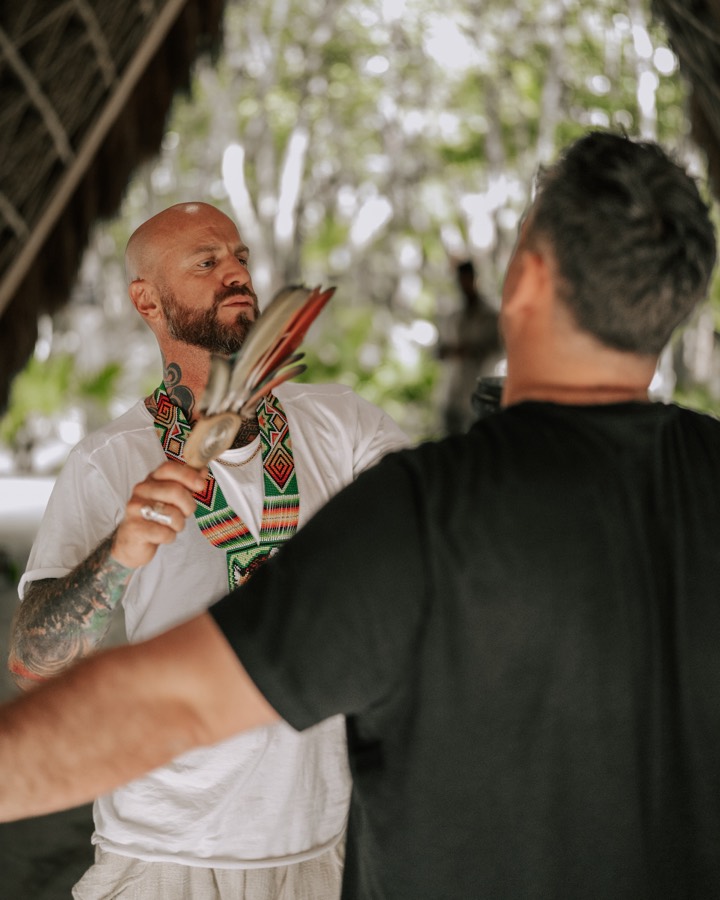 A facilitator blessing a participant with feathers before ceremony