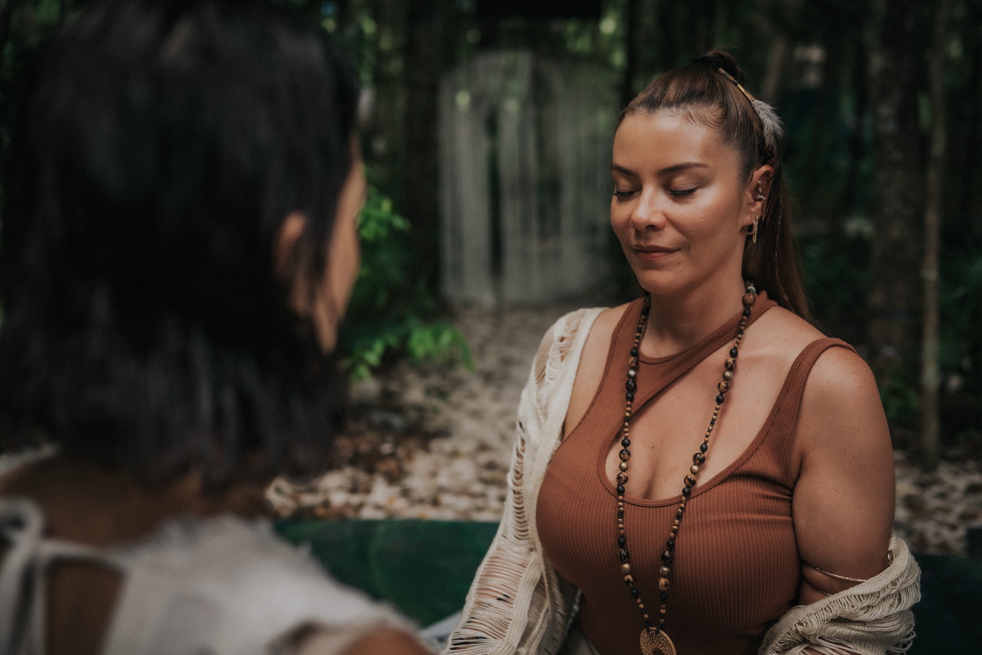 A woman sitting in calm stillness with a facilitator in the jungle