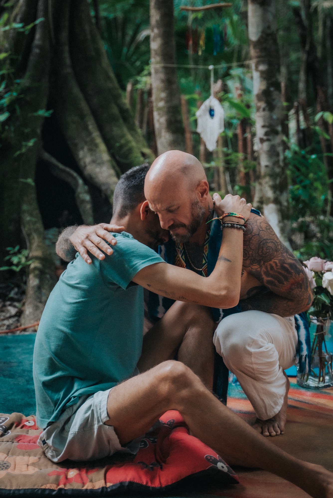Two men embracing in a jungle ceremony space at a Tiger Soul retreat